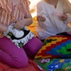 Barn i ett lektält fyllt av Magaloogi kuddar. Ett av barnen stoppar ner handen i en liten miniväska med dragkedja.