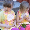 Barnförkläde i gult och rosa med blommor och virkade dukar som dekoration