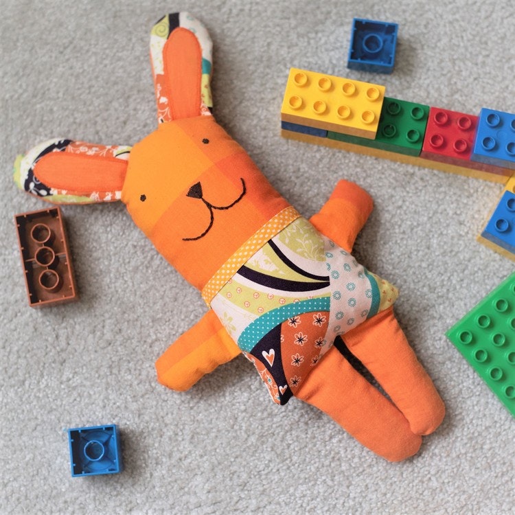 Tygdjur, gosedjur, mjukdjur. Djurkompis kanin bland Lego Duplo. Sydd av återbrukstextilier i orange färgskala.