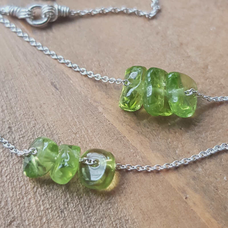 Två exempel på silverhalsband med peridot, månadssten för augusti. Stenarna varierar i nyans, form & uttryck.