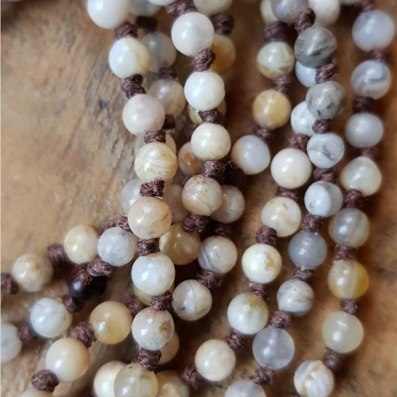 Detaljbild; halsbandet är skapat av pärlor av bambuagat i vackra jordnära nyanser.