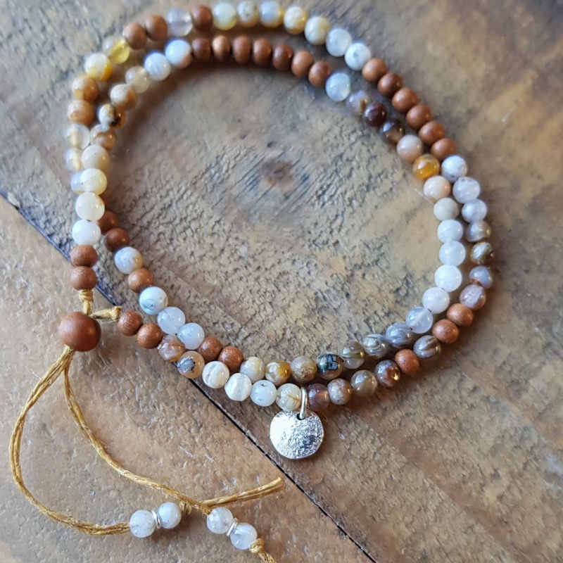 Armband med små pärlor av ljus sandelträ & agat i ljusa, jordnära nyanser. En handgjord månberlock i silver som detalj.