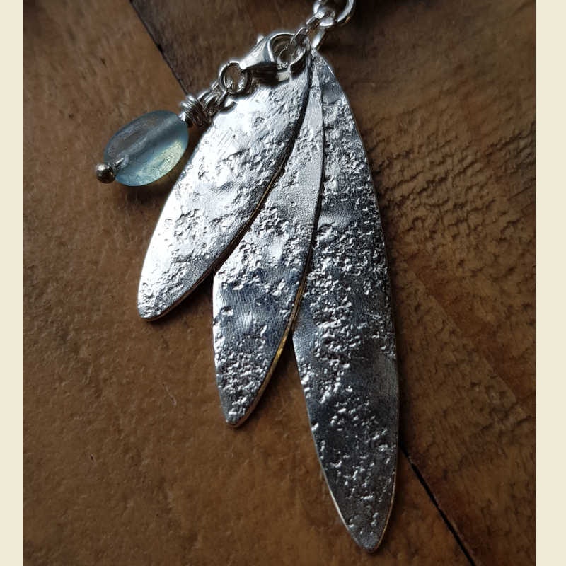 Handgjord silverberlock i form av tre smala blad samt en extra liten kristallberlock.