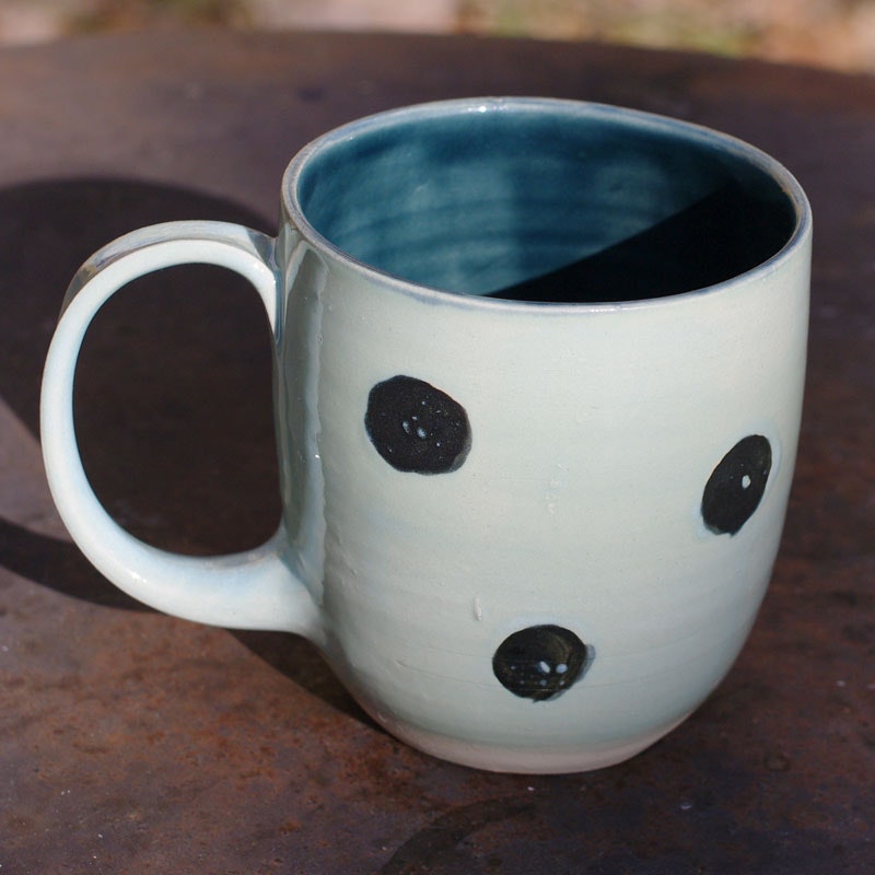 Lys blå kaffekopp med sorte prikker