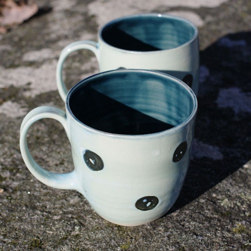 Lys blå kaffekopp med sorte prikker
