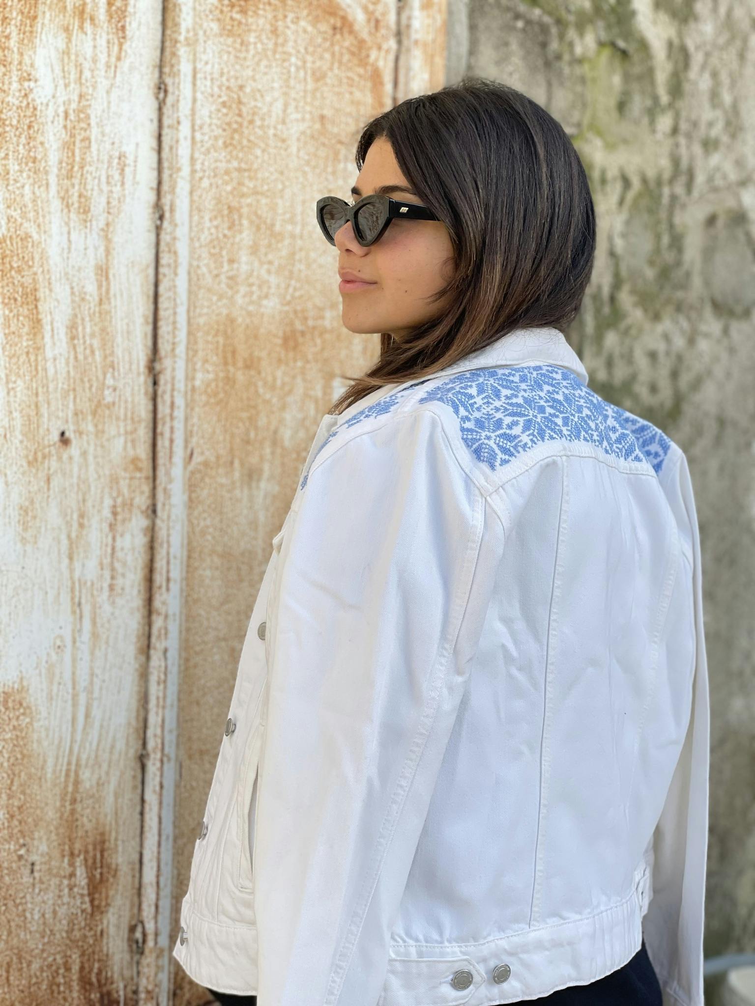 Moon of Bethlehem hand embroidered with love by woman artisan in Jordan on a white denim jacket with long sleeves. Featuring patch pockets on the chest, welt pockets at the waist, belt loops at the ba