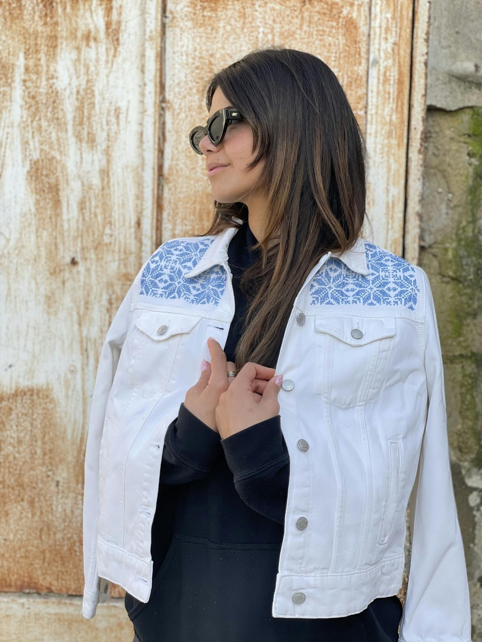 Moon of Bethlehem hand embroidered with love by woman artisan in Jordan on a white denim jacket with long sleeves. Featuring patch pockets on the chest, welt pockets at the waist, belt loops at the ba