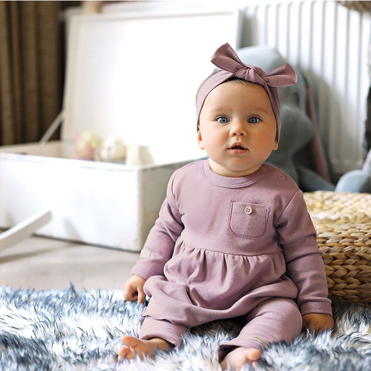Bebis som sitter med lila tunika från kollektionen Simply