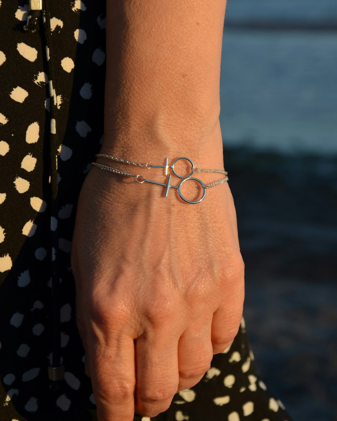 Silverarmband med kvinnotecknet  Venus. Två stycken armband på en hand.