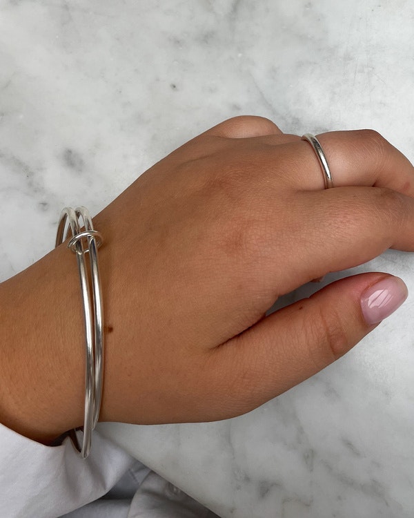 Handgjort armband i silver. Bestående av två ringar som hålls ihop med en liten ring. Sitter på arm.