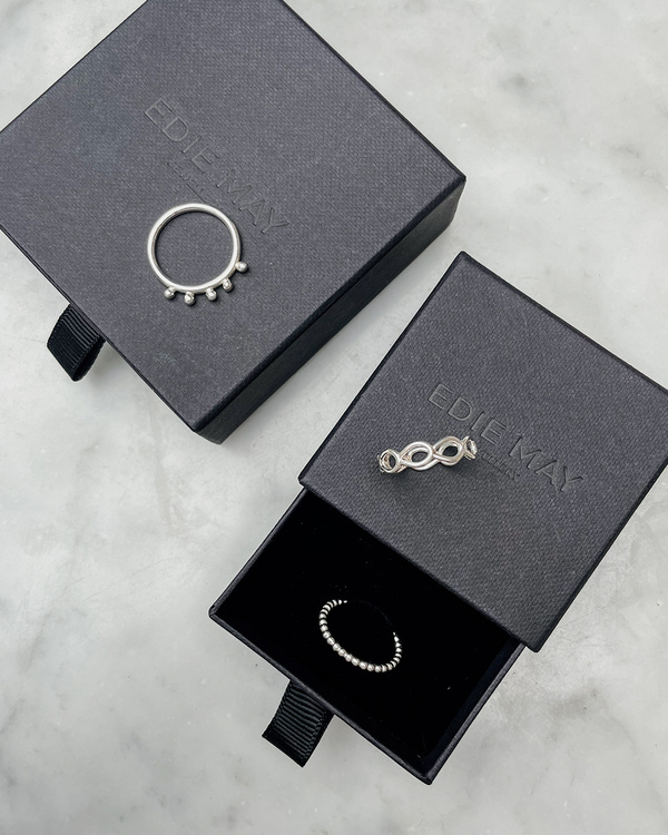 Handgjord kulformad ring i silver. Bilden visar ringen med andra ringar på en smyckesask.