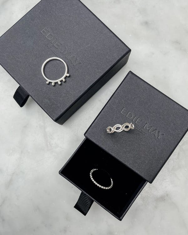 Handgjord kulformad ring i silver. Bilden visar ringen med andra ringar på en ask.
