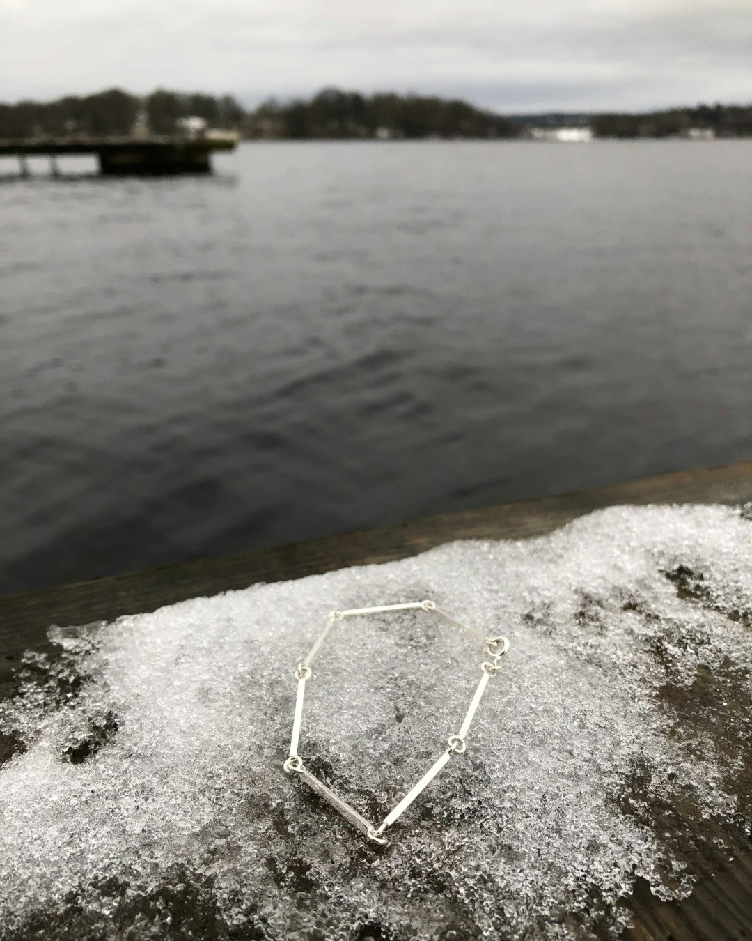 Unikt armband tillverkat av fyrkantig silvertråd och små öglor. Vid hav med is.