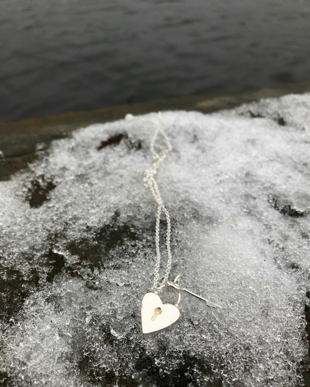 Halsband i återvunnet silver med hjärtformat hänglås och nyckel. På is.