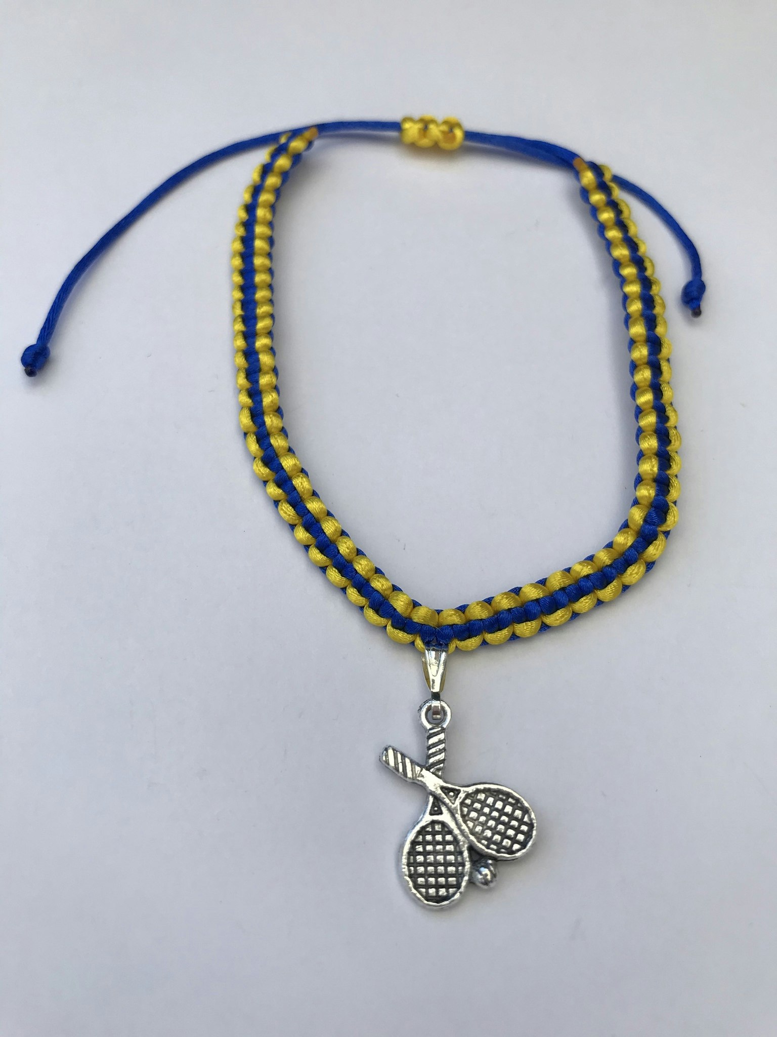 Makraméarmband i blått och gult med padel berlock i antikfärgat silver