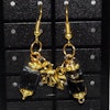 örhänge med svart akrylfyrkantig pärla och rosetter i färg guld
