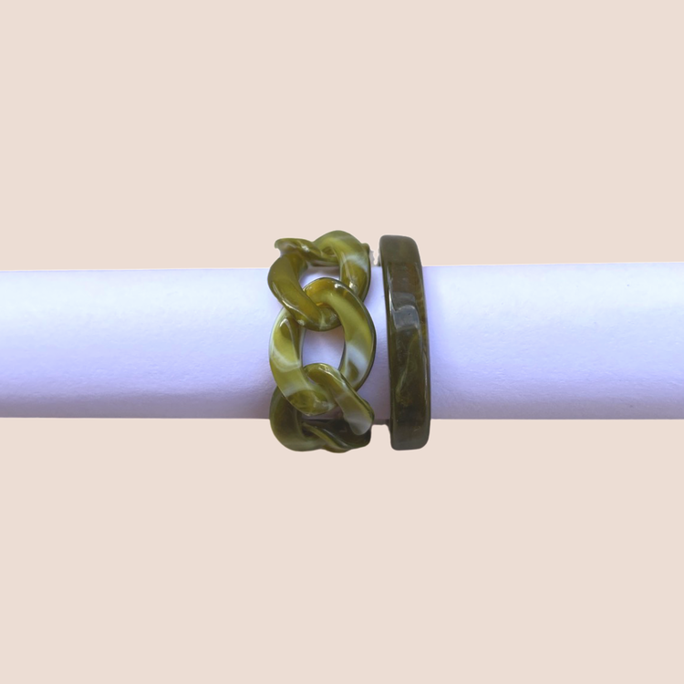 Mörkgrönt set med ringar av plast och kedjor som smycken