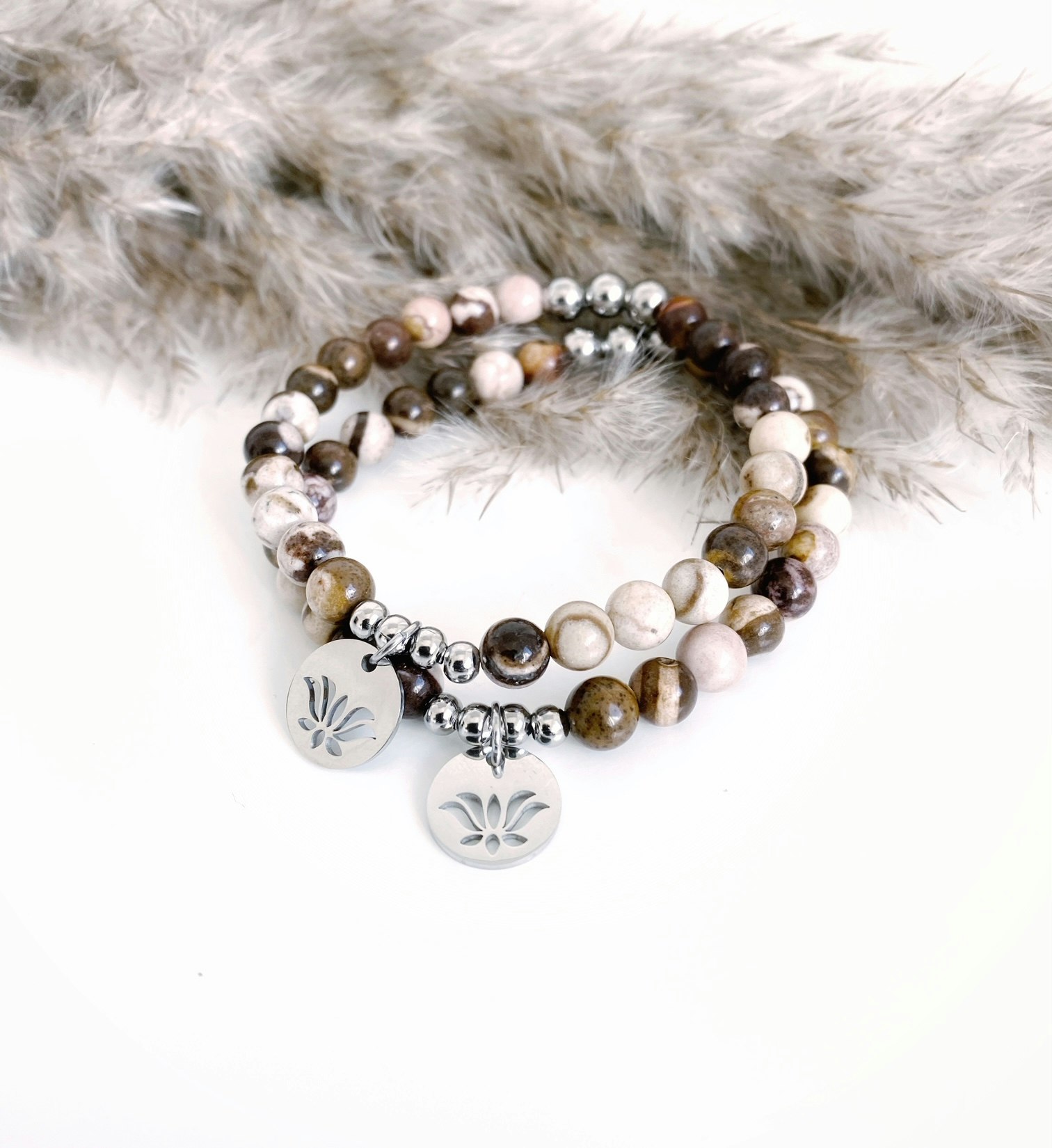 Armband med stenen zebra jaspis och symbolen lotusblomma som berlock som är i rostfritt stål.