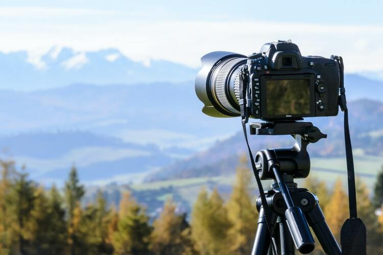 En fotokamera på stativ som är riktad mot bergsområdet. Illusterar bevisning i ärenden om strandskydd.