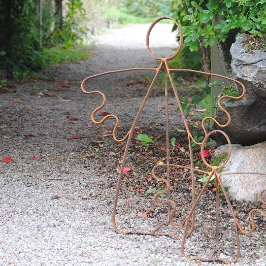 Stor och liten Änglavakt från MIA´s smedja. Änglarna står vid en pergola i en vacker trädgård.