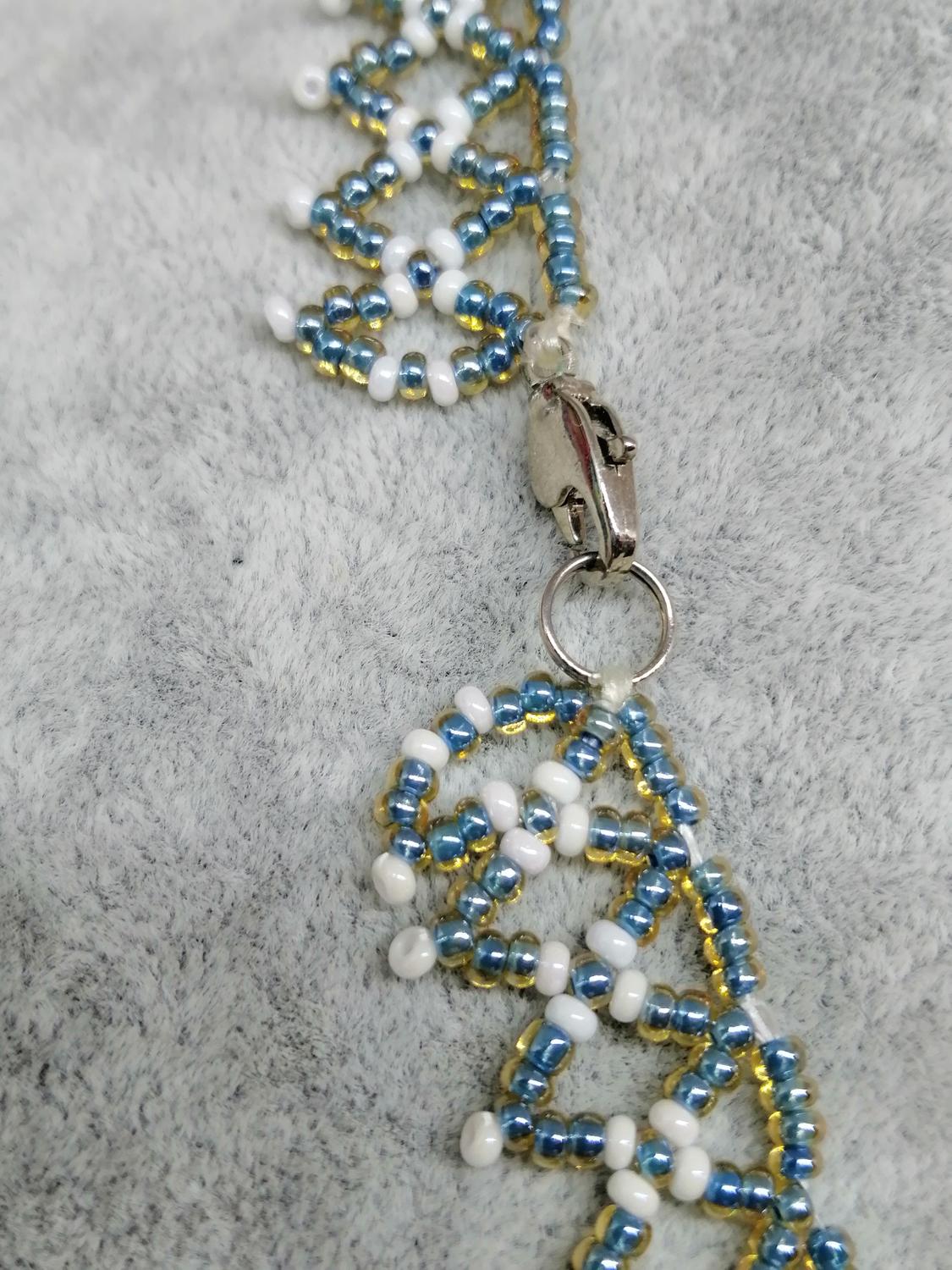 Bijouteri smycke halsband kort vävt trätt små små turkos vita pärlor spetsform