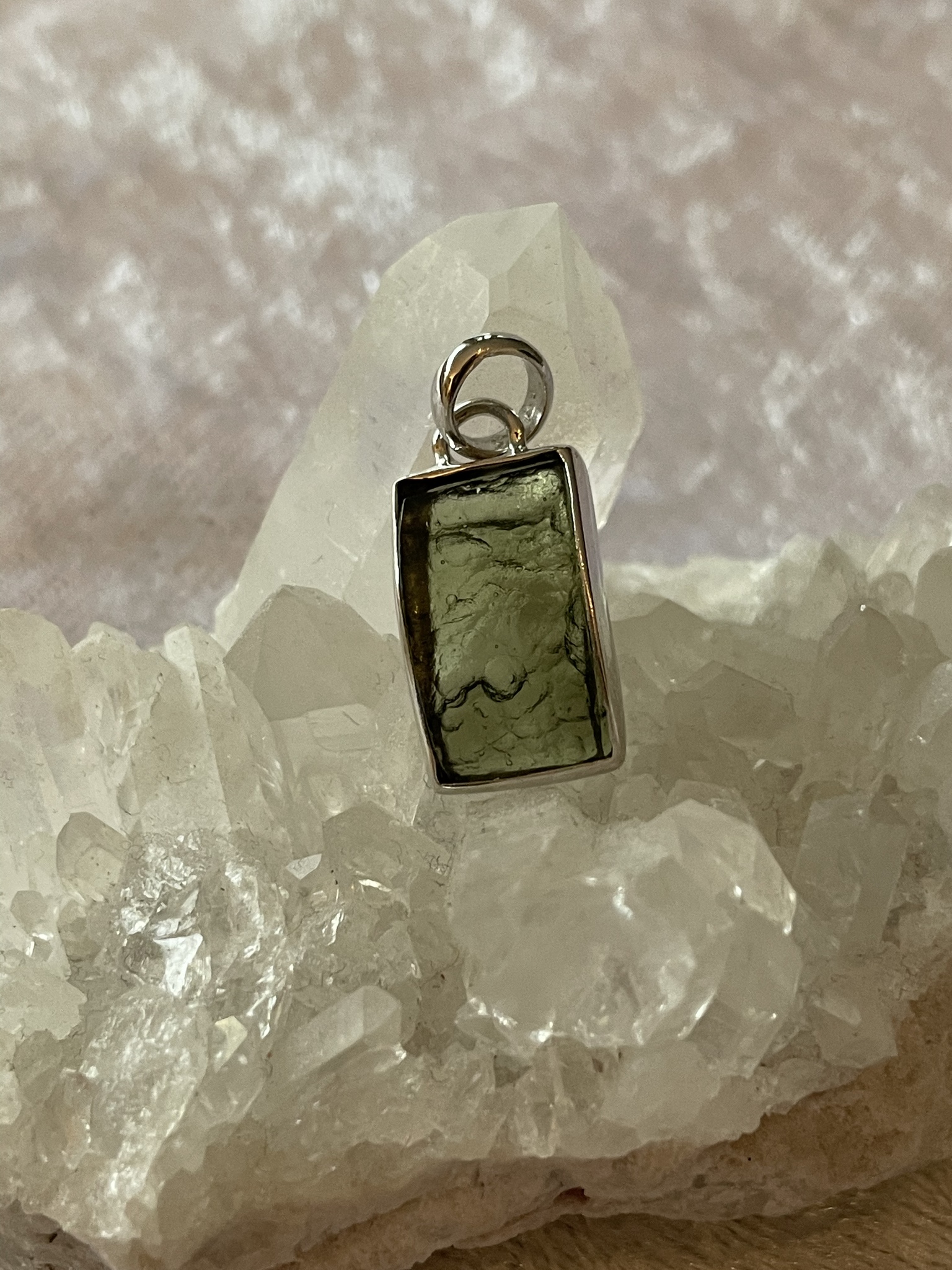 På bilden visas ett vackert silverhänge med en grön Moldavit