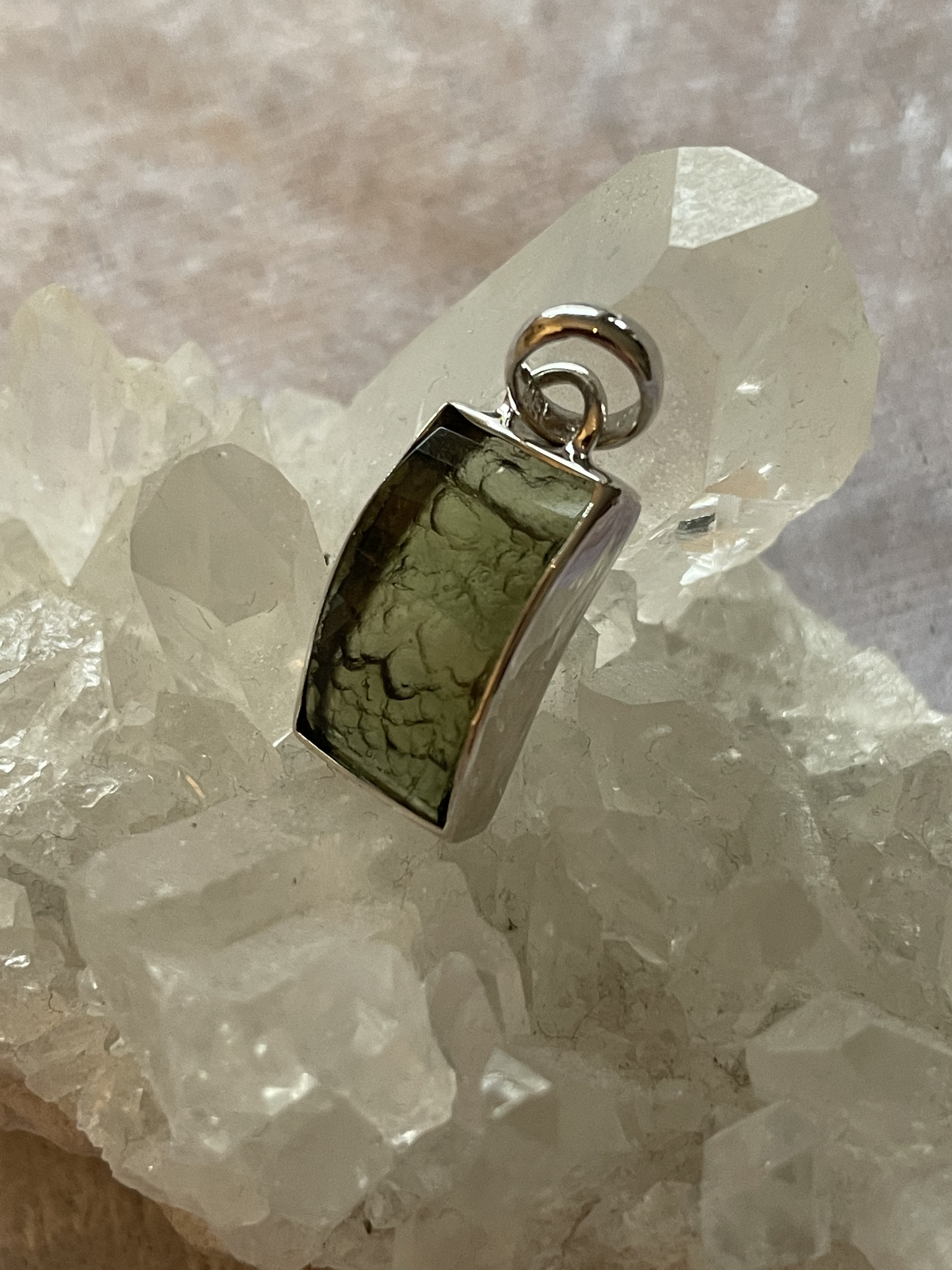 På bilden visas ett vackert silverhänge med en grön Moldavit
