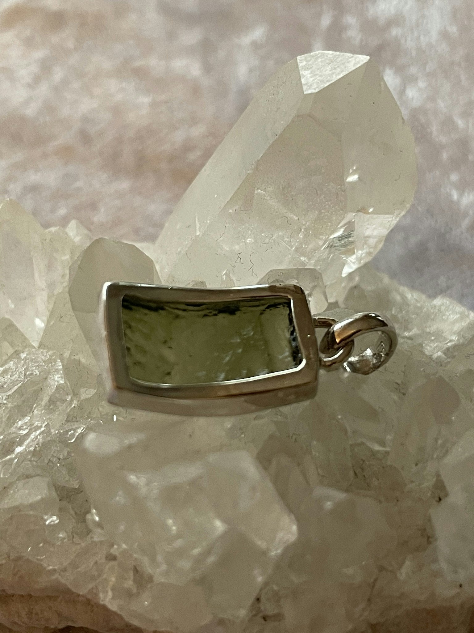 På bilden visas baksidan på ett vackert silverhänge med en grön Moldavit