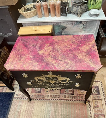 Svart byrå med rosa marmor.