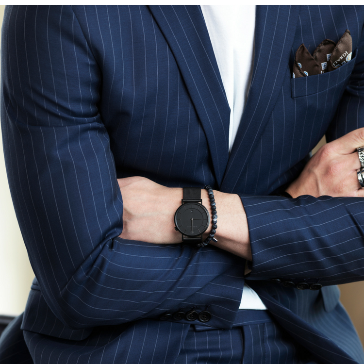 En klocka i svart meshstål och svart urtavla för herr- på modell.