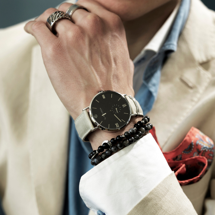 En klocka med beige läderrem och svart urtavla för herr- på modell.
