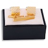 Set med mönstrade kvadratiska guldfärgade manschettknappar och slipsnål i ask