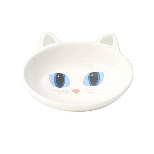 En vit kattmatskål i keramik som är formad som ett kattansikte. Inuti skålen ses både ögon och morrhår.