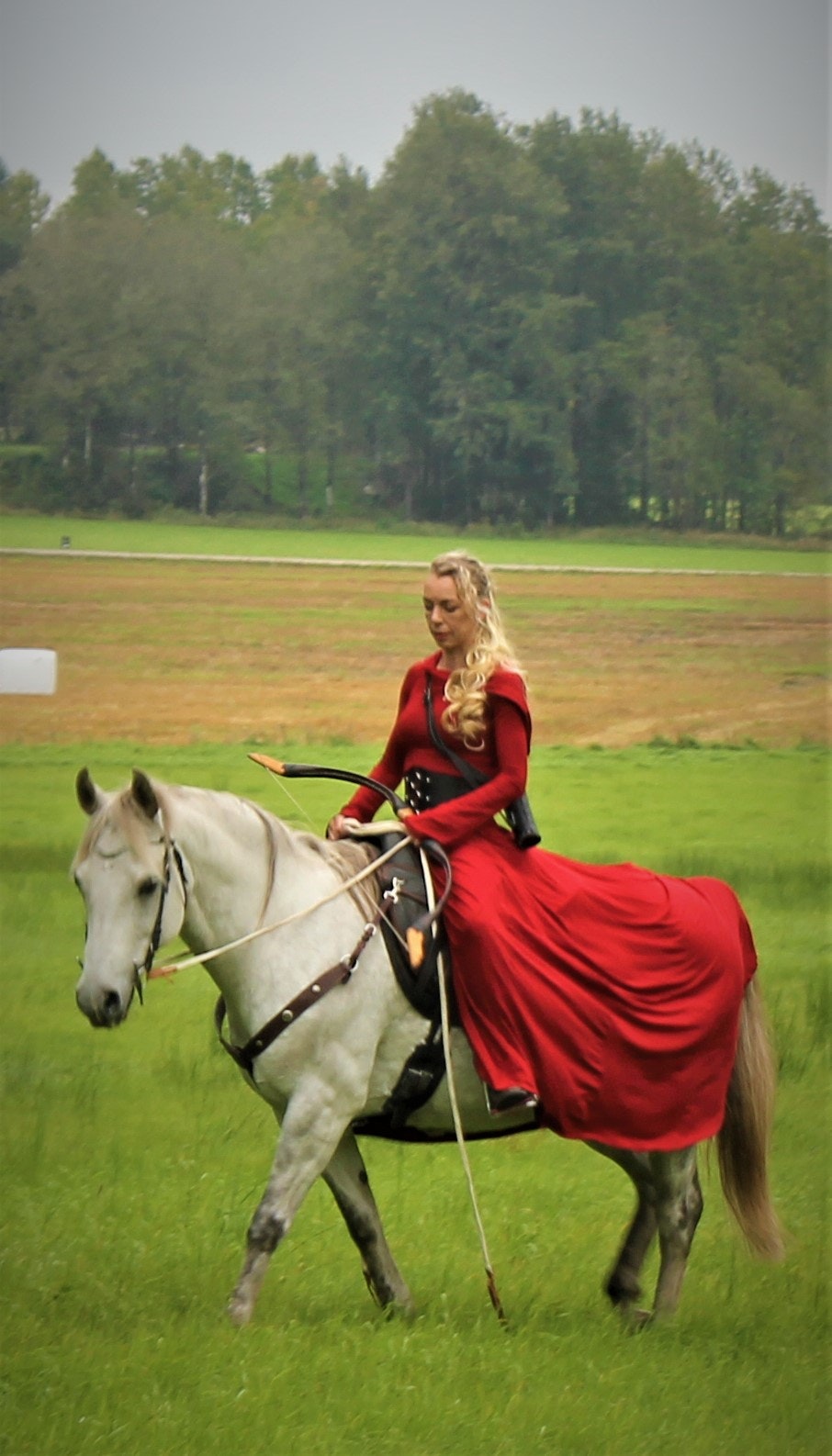 vikingklänning röd på hästryggen med pilbåge
