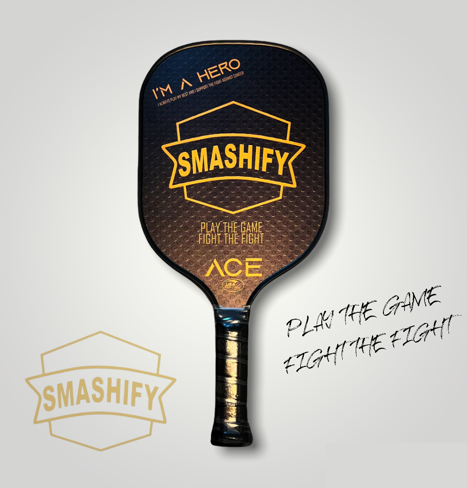 En bild på ett svart och gult pickleballrack, modellen heter Smashify ACE pickleball, med slogan play the game fight the fight och Smashify´s logga