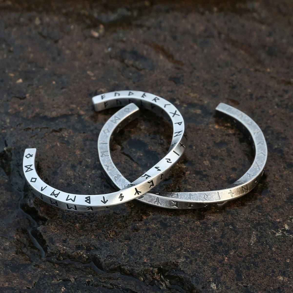 Tvinnet armring med runer, utført i rustfritt stål.