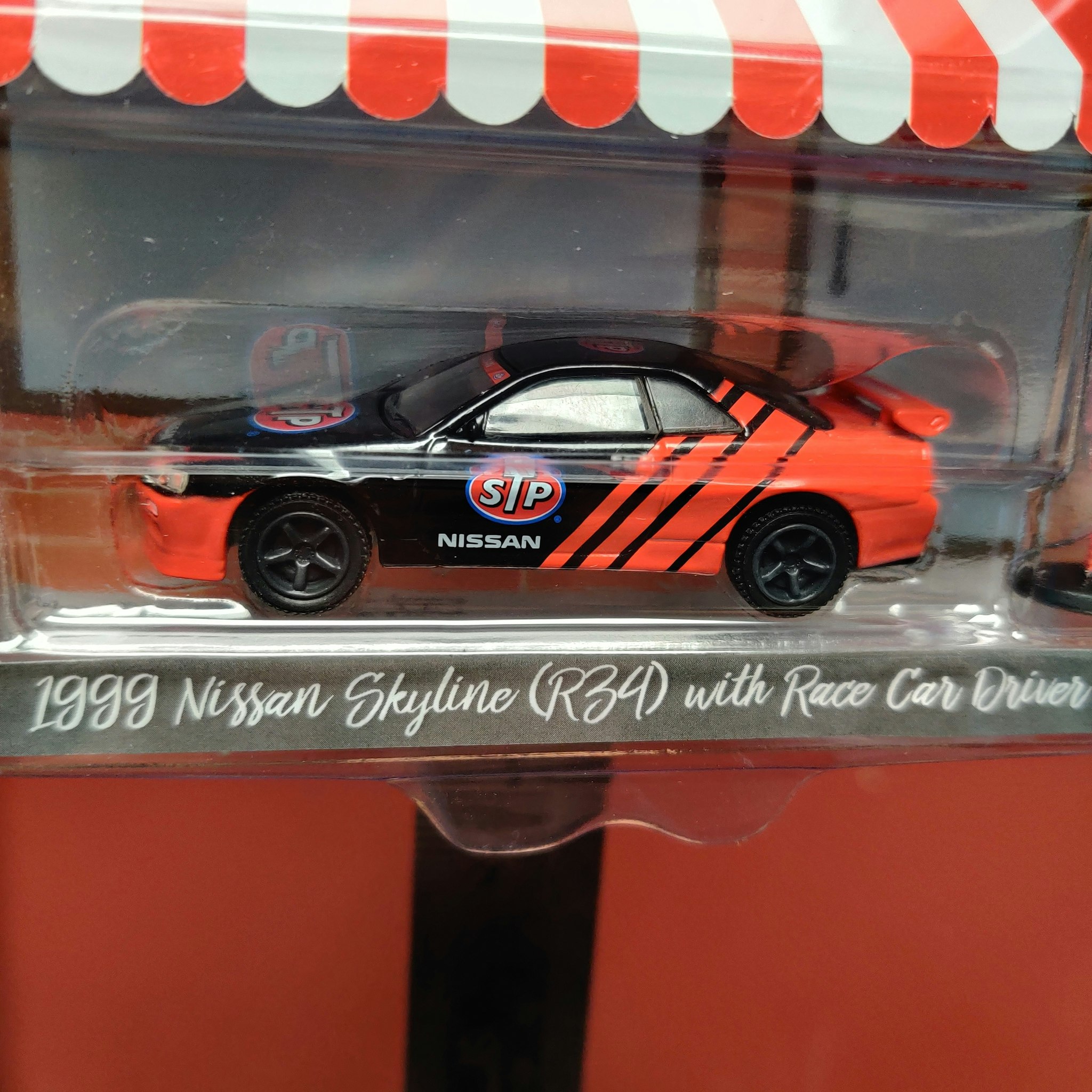 Skala 1/64 Nissan Skyline R34 1999 med förare "Hobby Shop" fr Greenlight