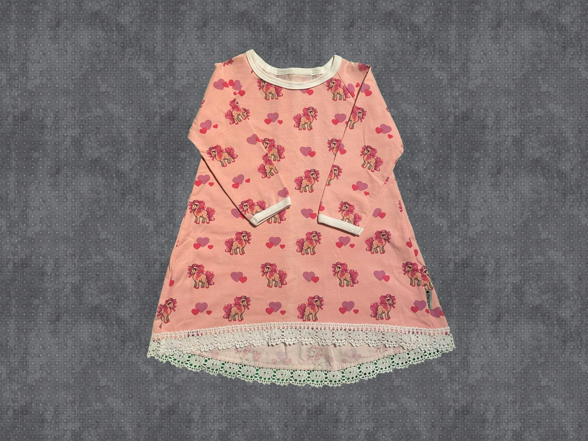 Klänning med veck bak. Hästar med rosa botten och spets nertill. Stl 80