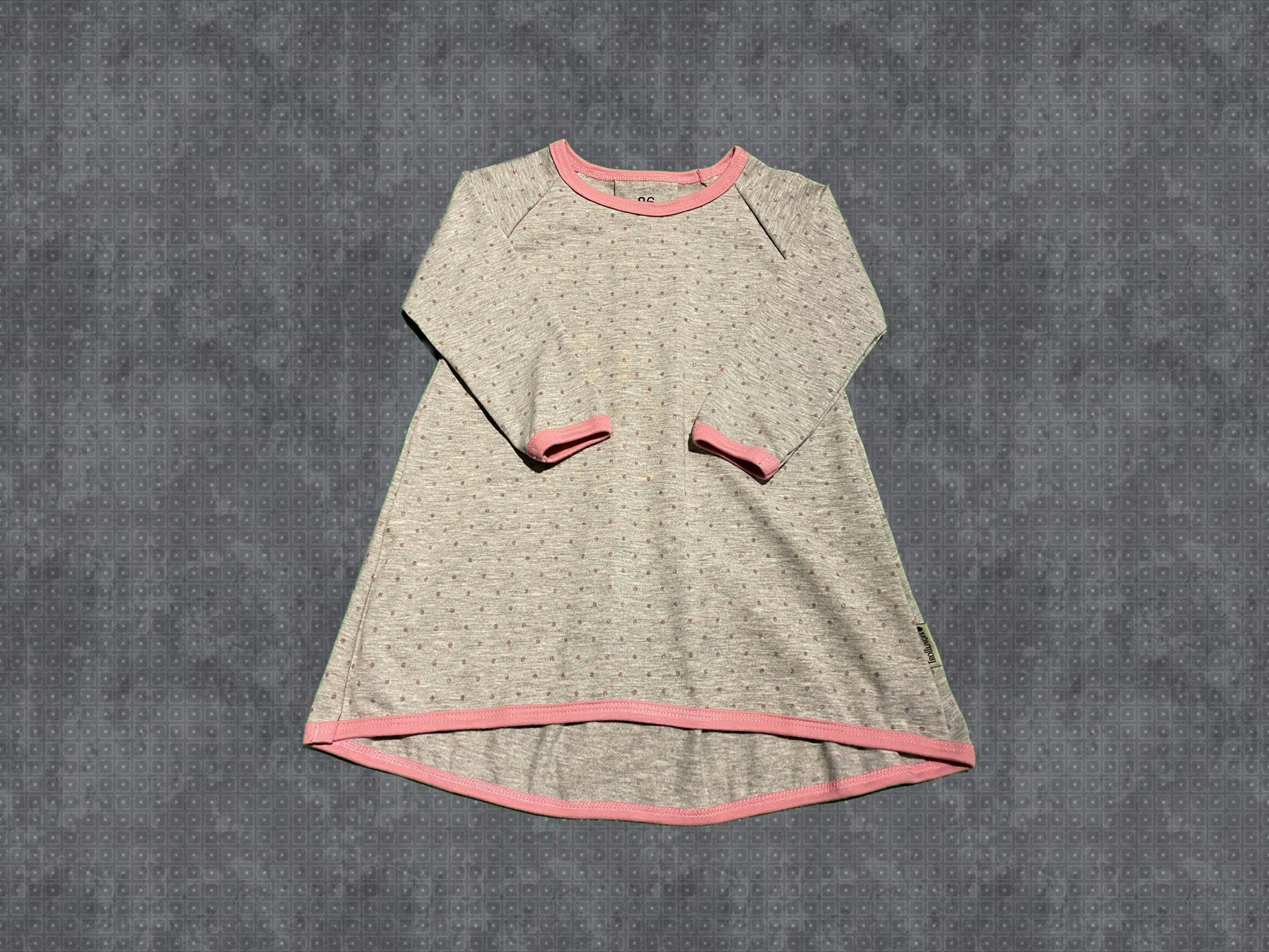 Klänning med veck bak.  Grå botten med rosa glittriga prickar.