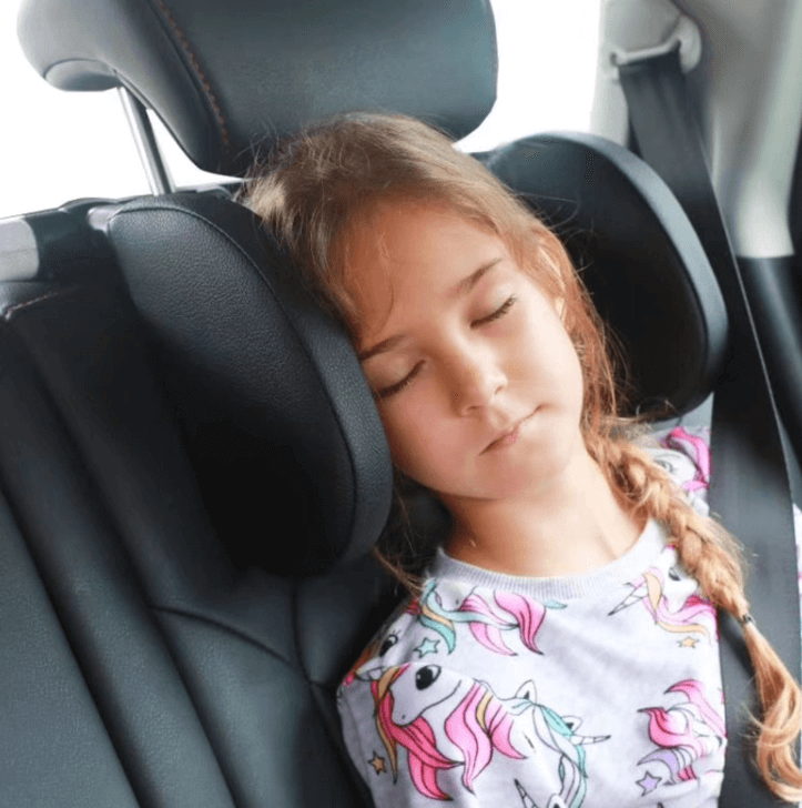 Barn som vilar mot ett nackstöd i bilen