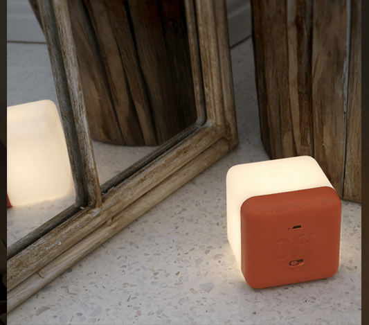 Fin nattlampa form av en vit kub med orange botten som lyser upp ett rum