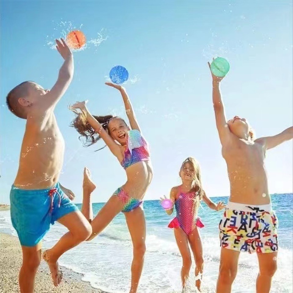 Barn som leker med vattenballonger på en strand