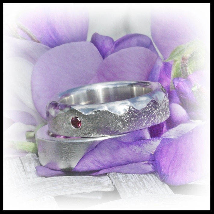 Blid diamantring i silver med högblanka vågformationer på den ena kanten och en diamantslipad matterad flack yta och med en lila diamant 0,05ct. Ringar från Alv Design