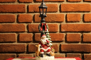 Sittende nisse ved stolpe med lys.