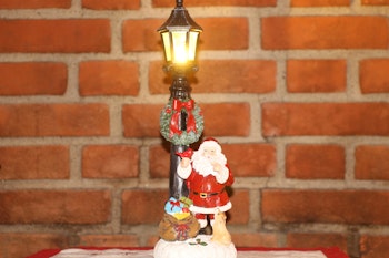 Stående nisse ved stolpe med lys.