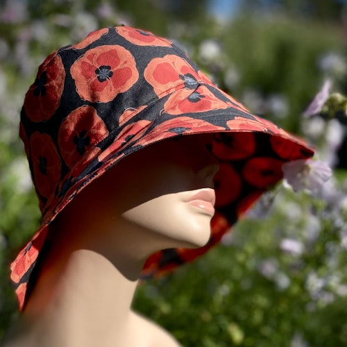 classy n sassy solhatt med röda vallmos på svart canvastyg