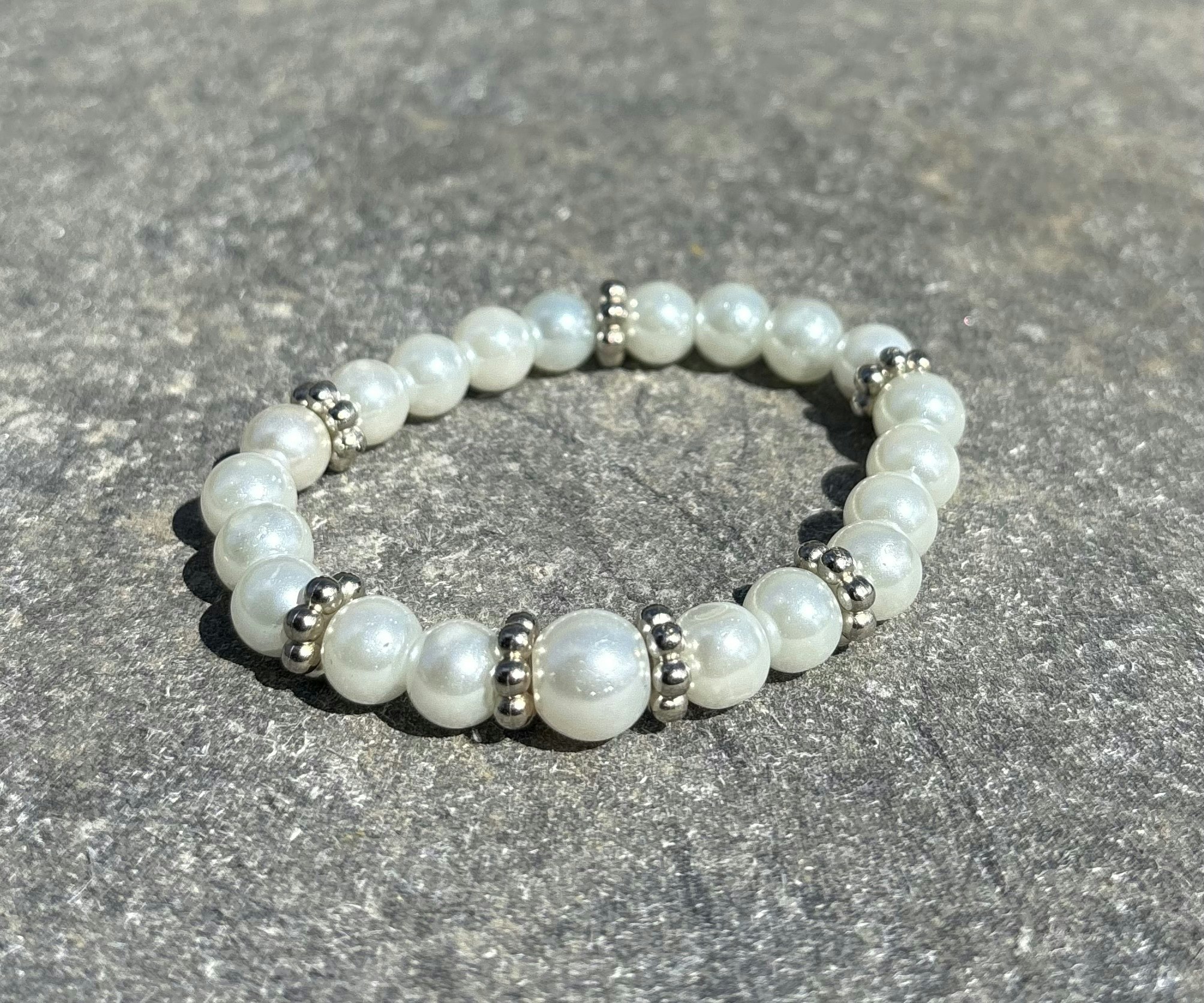 Armband med vita glaskulor och silvriga detaljer