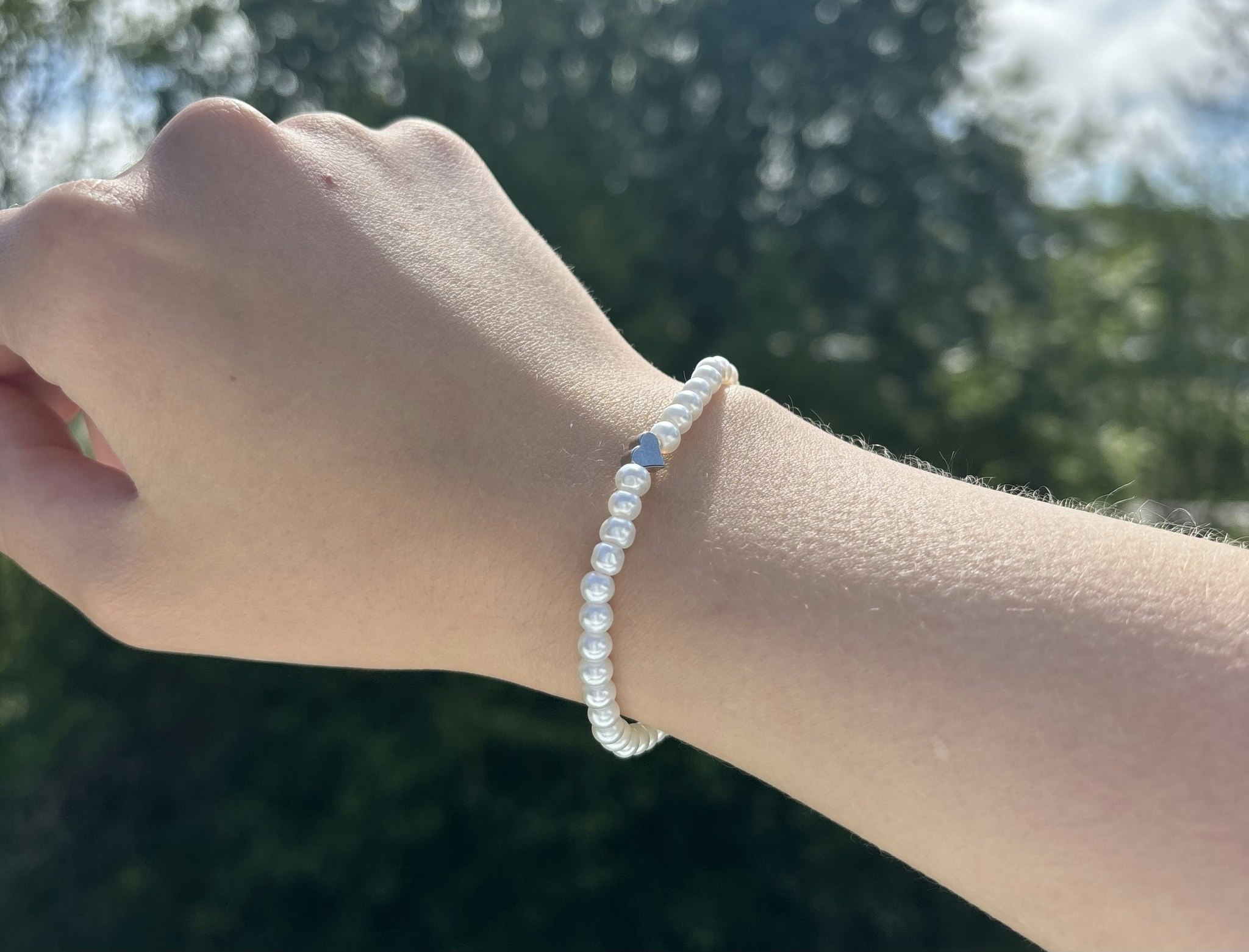Vitt armband med glaskulor och ett silvrigt hjärta