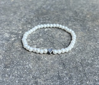 Vitt armband med glaskulor och ett silvrigt hjärta