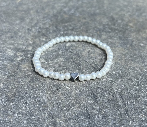Vitt armband med glaskulor och ett silvrigt hjärta